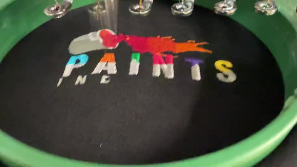 Close view of a multicolour embroidered PAINTS logo in the embroidery frame